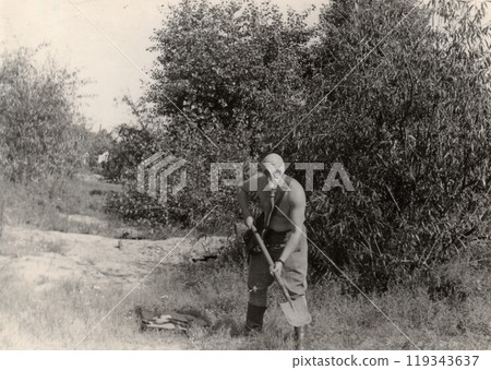 Vintage photo of a soldier in a gas mask without a tunic. Humor. The man is holding a shovel. Vintage photo of a soldier in a gas mask without a tunic. Humor. The man is holding a shovel. 119343637