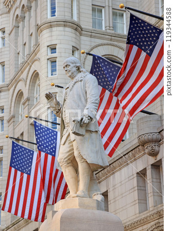 Old Post Office building with Benjamin Franklin Statue surrounded by American flags, Washington DC, United States 119344588