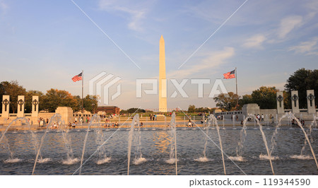 People enjoying the basin and fountains of The World War II Memorial. The Washington Monument is on the background. 119344590