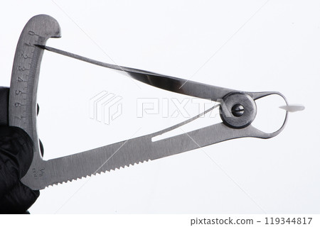 Thickness of high-quality ceramic veneer is measured with a micrometer. White background. 119344817