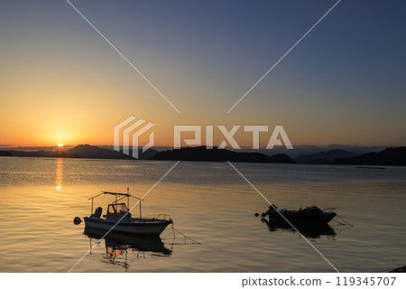 The sun rising over a fishing port in Setouchi and the Sun Road stretching out to sea 119345707
