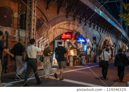 A view of Tokyo at night under a railway overpass. Photographing restaurant food, office workers returning home from work, and other people's backs. A view of Tokyo at night under a railway overpass. Photographing restaurant food, office workers returning home from work, and other people's backs. 119346329