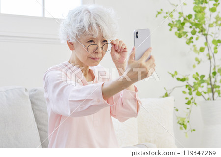 Senior woman with presbyopia looking at a smartphone 119347269
