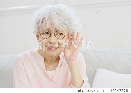 Hearing-impaired senior woman in the living room 119347278