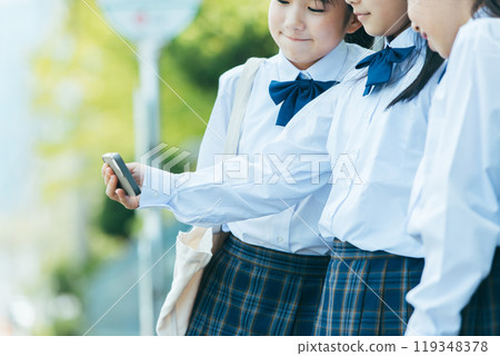 Female student looking at smartphone at bus stop Female student looking at smartphone at bus stop 119348378