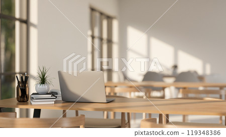 A laptop on a wooden table in a minimalist Scandinavian coffee shop co-working space or library. A laptop on a wooden table in a minimalist Scandinavian coffee shop co-working space or library. 119348386