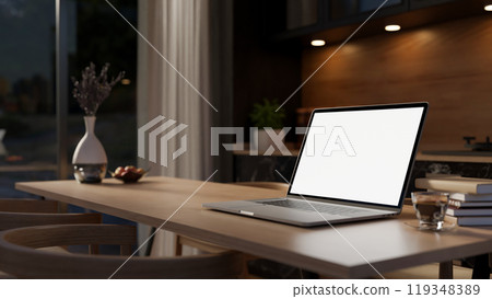 A close-up of a laptop mockup on a hardwood dining table in a contemporary, luxurious kitchen. 119348389
