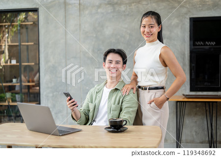 A handsome Asian businessman and an attractive Asian businesswoman are in the office together. 119348692