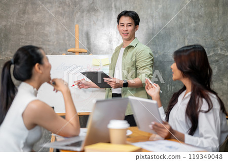 A smart Asian businessman is leading the meeting, speaking to his team and sharing his ideas. 119349048