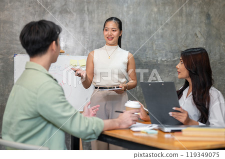 A confident and professional Asian businesswoman is speaking during a meeting with her team. A confident and professional Asian businesswoman is speaking during a meeting with her team. 119349075