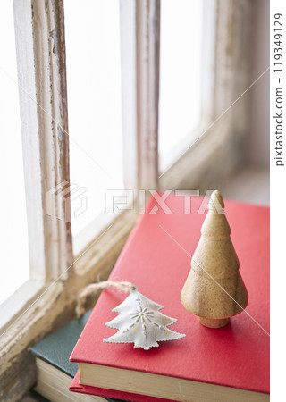 Old books and Christmas accessories placed on an antique windowsill Old books and Christmas accessories placed on an antique windowsill 119349129