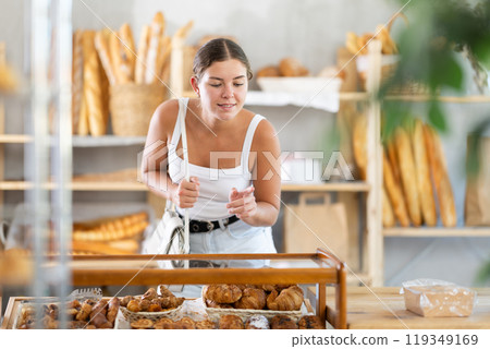 Young female customer chooses croissants in bakery 119349169