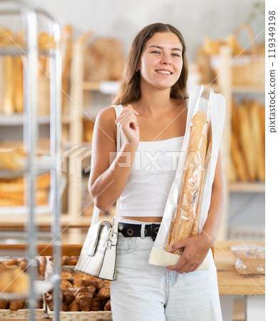 Positive young girl holding baguettes in plastic bag in bakery Positive young girl holding baguettes in plastic bag in bakery 119349198