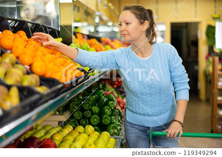 Portrait of calm adult European woman buying local citrus tangerines during shopping in supermarket Portrait of calm adult European woman buying local citrus tangerines during shopping in supermarket 119349294