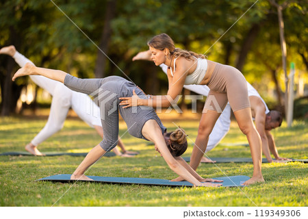 Coach corrects downward facing dog position, helps to perform exercise correctly. 119349306