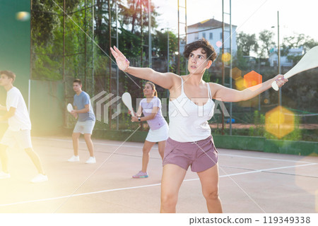 Young Latina playing pelota on open court on summer day Young Latina playing pelota on open court on summer day 119349338