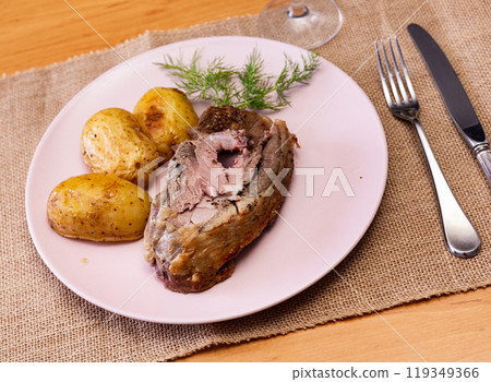 Roasted leg of lamb served with potatoes 119349366