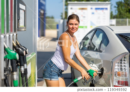 Woman refuelling her car at petrol filling station 119349392