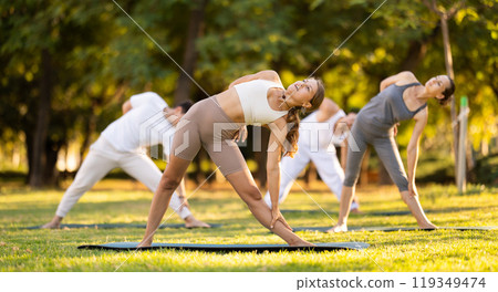 Girl leading outdoor group yoga class in summer park Girl leading outdoor group yoga class in summer park 119349474