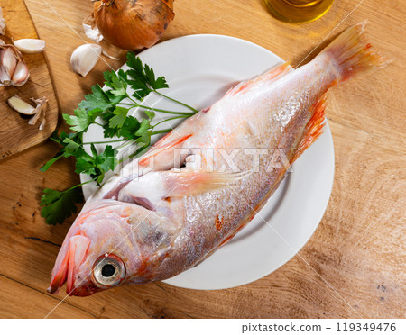 Raw whole red palometa fish with garlic and parsley on desk 119349476