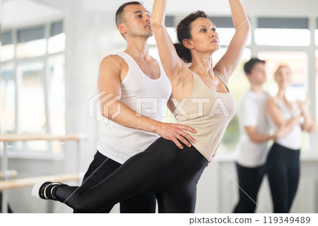 Ballet dancer providing support of female partner in challenging movements Ballet dancer providing support of female partner in challenging movements 119349489