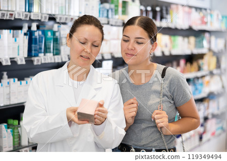 Woman pharmacist helping woman customer to choose cosmetic product 119349494