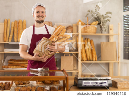 Young male seller with baguettes in basket 119349518