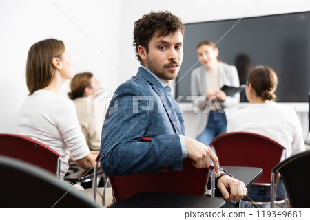 Portrait of successful young man participating in language courses with group of people in classroom Portrait of successful young man participating in language courses with group of people in classroom 119349681