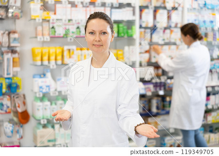 At pharmacy, apothecary waiting for customers and invites with gesture go to department of cosmetics 119349705