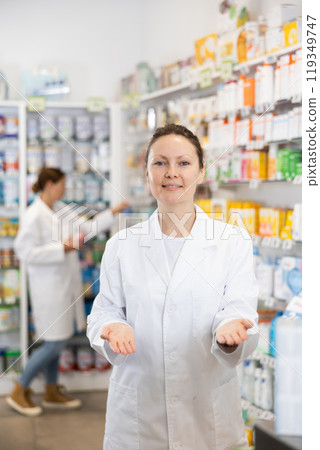 Adult female pharmacist in uniform posing in pharmacy Adult female pharmacist in uniform posing in pharmacy 119349747