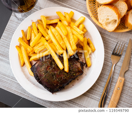 Roasted pork steak served with vegetable garnish of crispy fries 119349790
