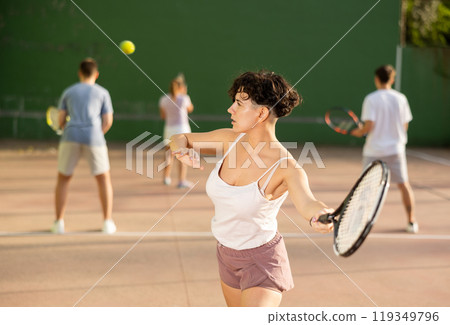 Woman playing frontenis with partners at sunny day, healthy lifestyle concept 119349796
