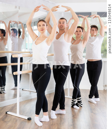 Group of dancers stand in fifth position at barre Group of dancers stand in fifth position at barre 119349814