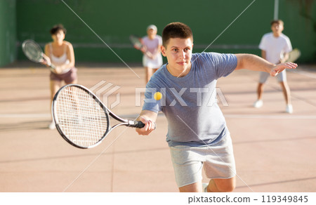 Active man with racket playing frontenis game on outdoor court Active man with racket playing frontenis game on outdoor court 119349845