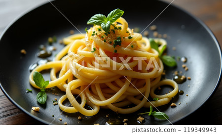 A serving of perfectly cooked spaghetti is elegantly presented on a black plate, garnished with fresh herbs and a sprinkle of cheese, creating an inviting culinary experience. 119349943