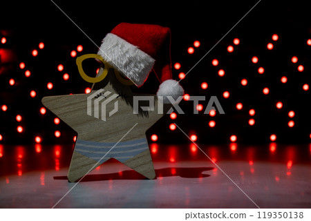 Wooden star with Santa's hat on dark bokeh light garland background. New year and Christmas preparation. Handmade eco-friendly decor. Sustainable Christmas decoration Wooden star with Santa's hat on dark bokeh light garland background. New year and Christmas preparation. Handmade eco-friendly decor. Sustainable Christmas decoration 119350138