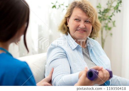 Asian caregiver woman or nurse training senior woman lifting dumbbell for arm exercise. 119350418