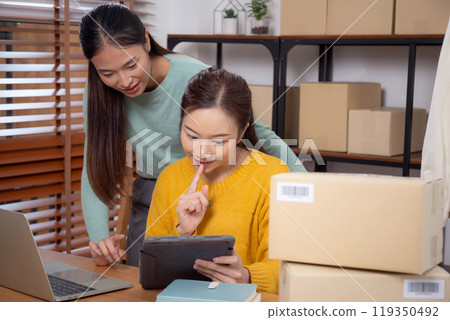 Two young asian woman working on tablet while managing and planning online business. Two young asian woman working on tablet while managing and planning online business. 119350492