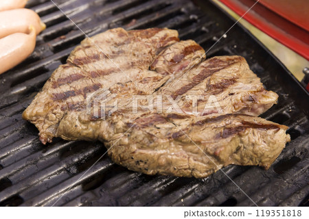 Steak meat and sausages grilled on a gas grill - barbecue image 119351818