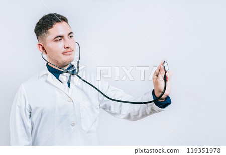 Male doctor holding stethoscope on white background. Portrait of latin doctor holding stethoscope with copy space Male doctor holding stethoscope on white background. Portrait of latin doctor holding stethoscope with copy space 119351978