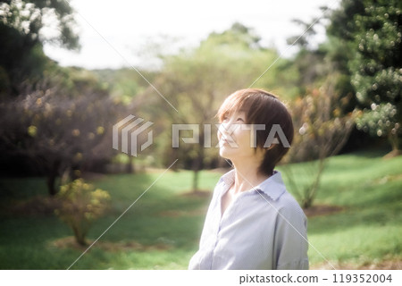 Smiling woman gazing at the sky among the trees 119352004