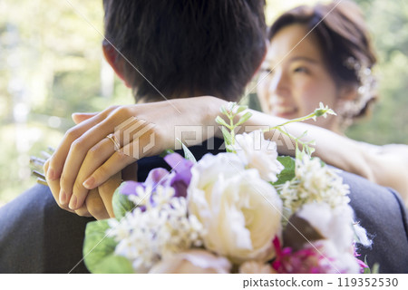 Bride and groom having an outdoor wedding ceremony. The hands of the bride embracing the groom. 119352530