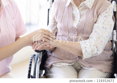 Care image: A caregiver holding a senior's hand 119352671