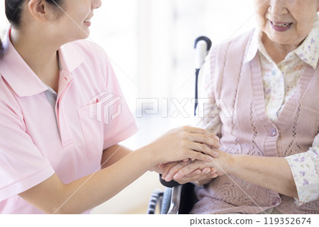 Care image: A caregiver holding a senior's hand 119352674