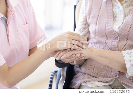 Care image: A caregiver holding a senior's hand 119352675