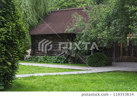 Wooden house made of logs among trees. Among the trees is a wooden log house Wooden house made of logs among trees. Among the trees is a wooden log house 119353634