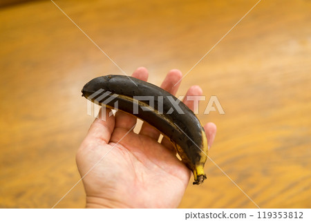 Hand holding a black banana 119353812