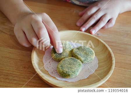 一個孩子的手正要吃撒有黃豆粉的草麻糬。 一個孩子的手正要吃撒有黃豆粉的草麻糬。 119354016