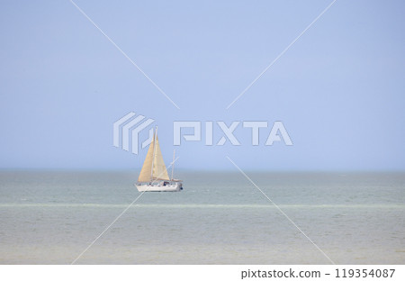 A Beautiful Sailing Boat Gently Gliding on the Calm Waters Beneath a Clear Blue Sky Today 119354087