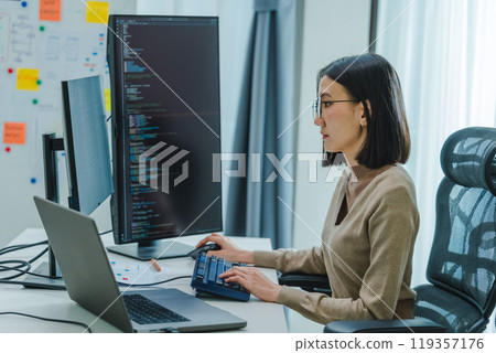 Asian prompt engineer develop coding app with software data sitting in front of computer monitor at office Asian prompt engineer develop coding app with software data sitting in front of computer monitor at office 119357176